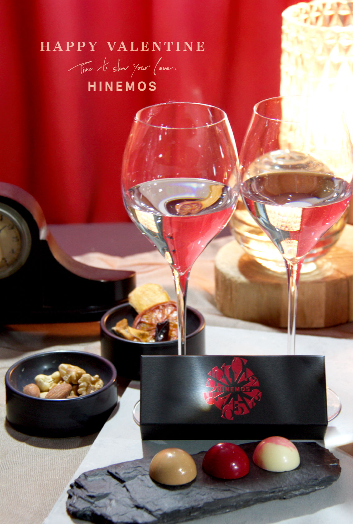 Two glasses of wine with chocolates and snacks for Valentine's Day celebration.