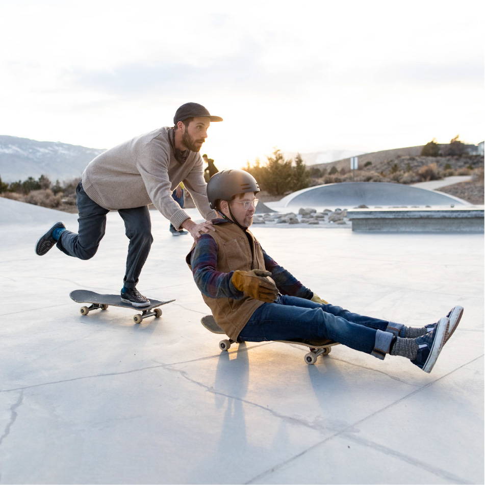 Man pushing friend on skateboard