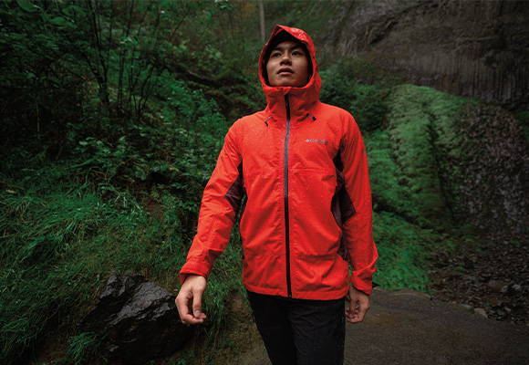 Man hiking in a forest in a Columbia Waterproof Rain Jacket