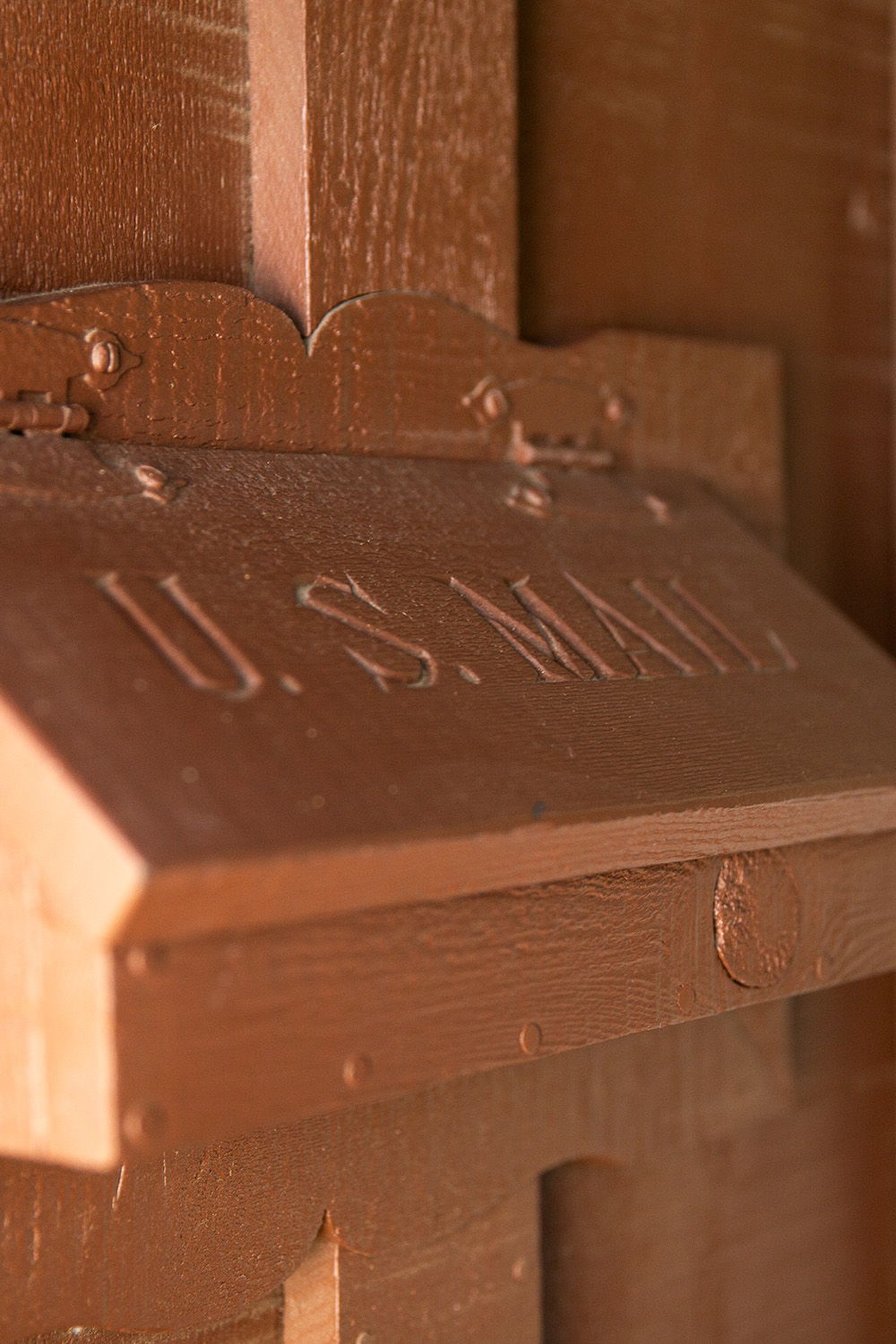 A wood mail slot on a vintage home with hand carved lettering reading 