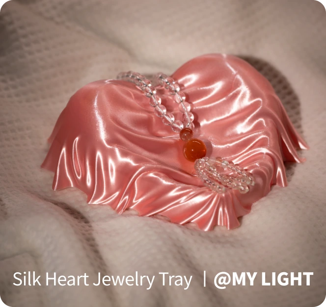 Silk heart-shaped jewelry tray with decorative items on a textured surface.