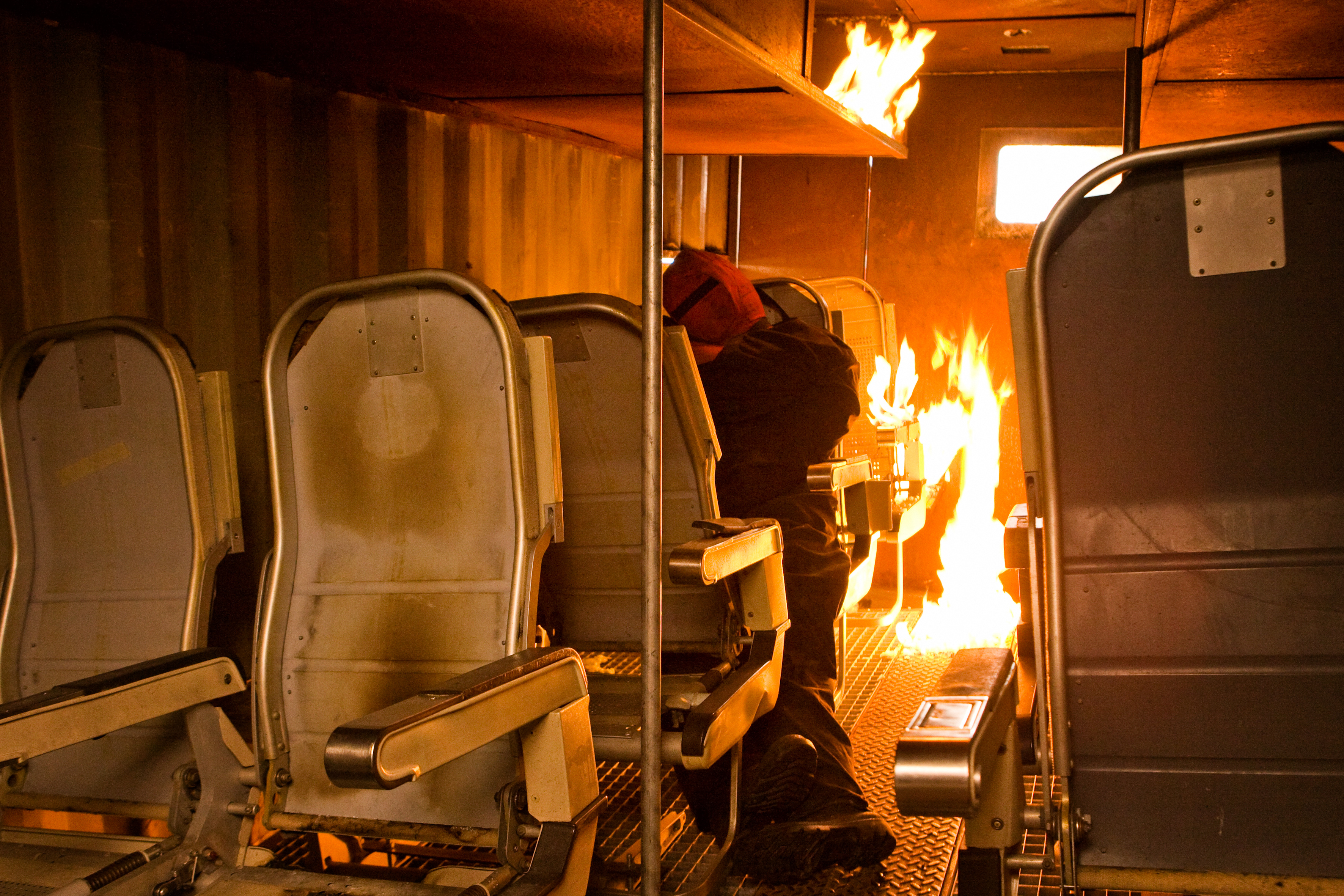 Interior of a burning aircraft with a firefighter responding to the fire.