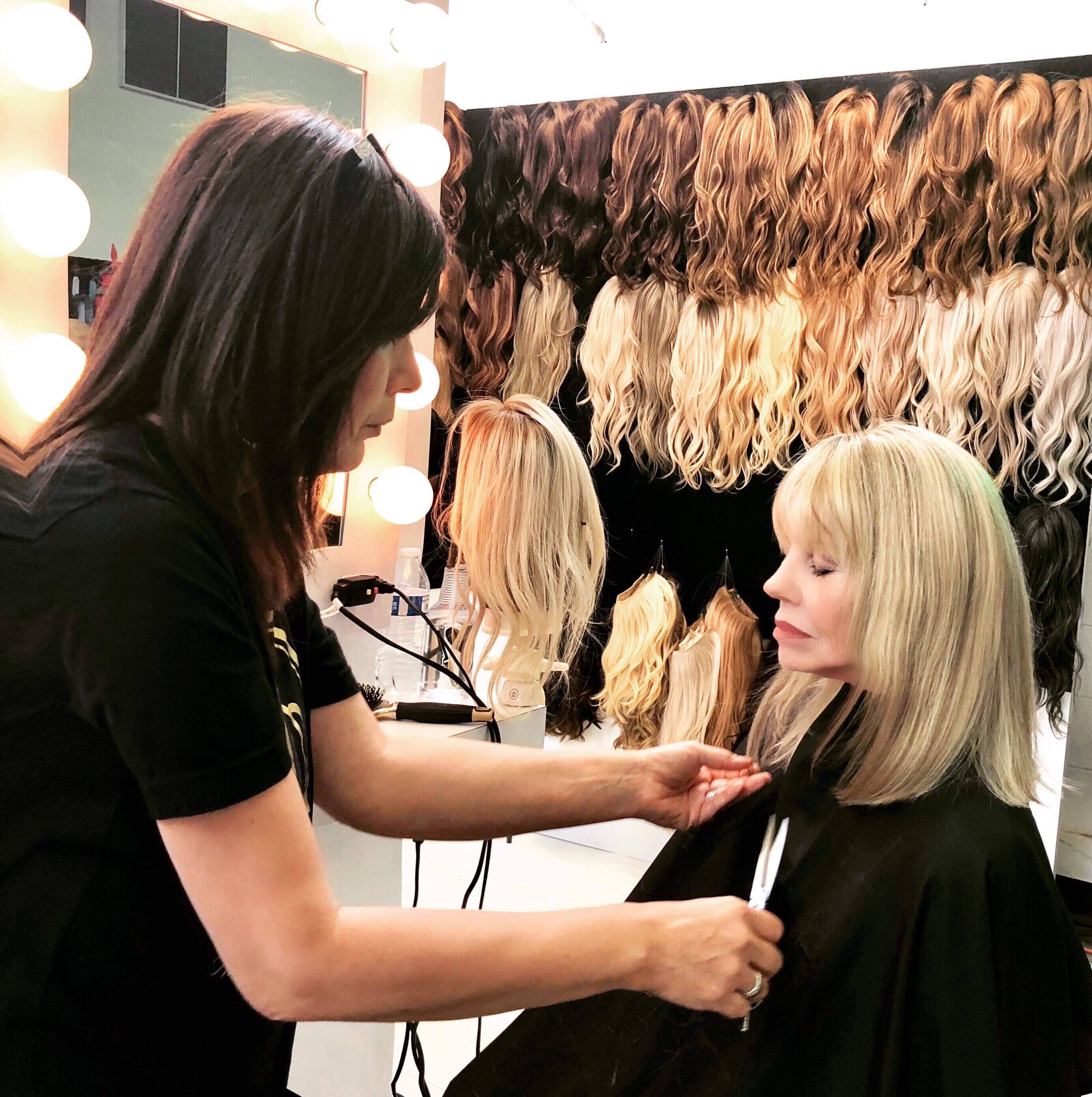 Person applying a wig on a woman