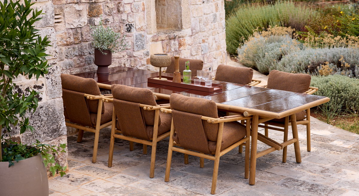 Outdoor Cane-Line dining table with chairs surrounded by greenery.