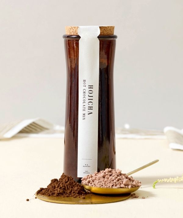 A glass container of chocolate powder with a cork stopper.