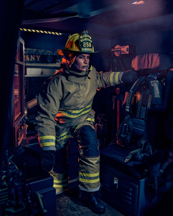 Firefighter in uniform preparing inside a fire truck.