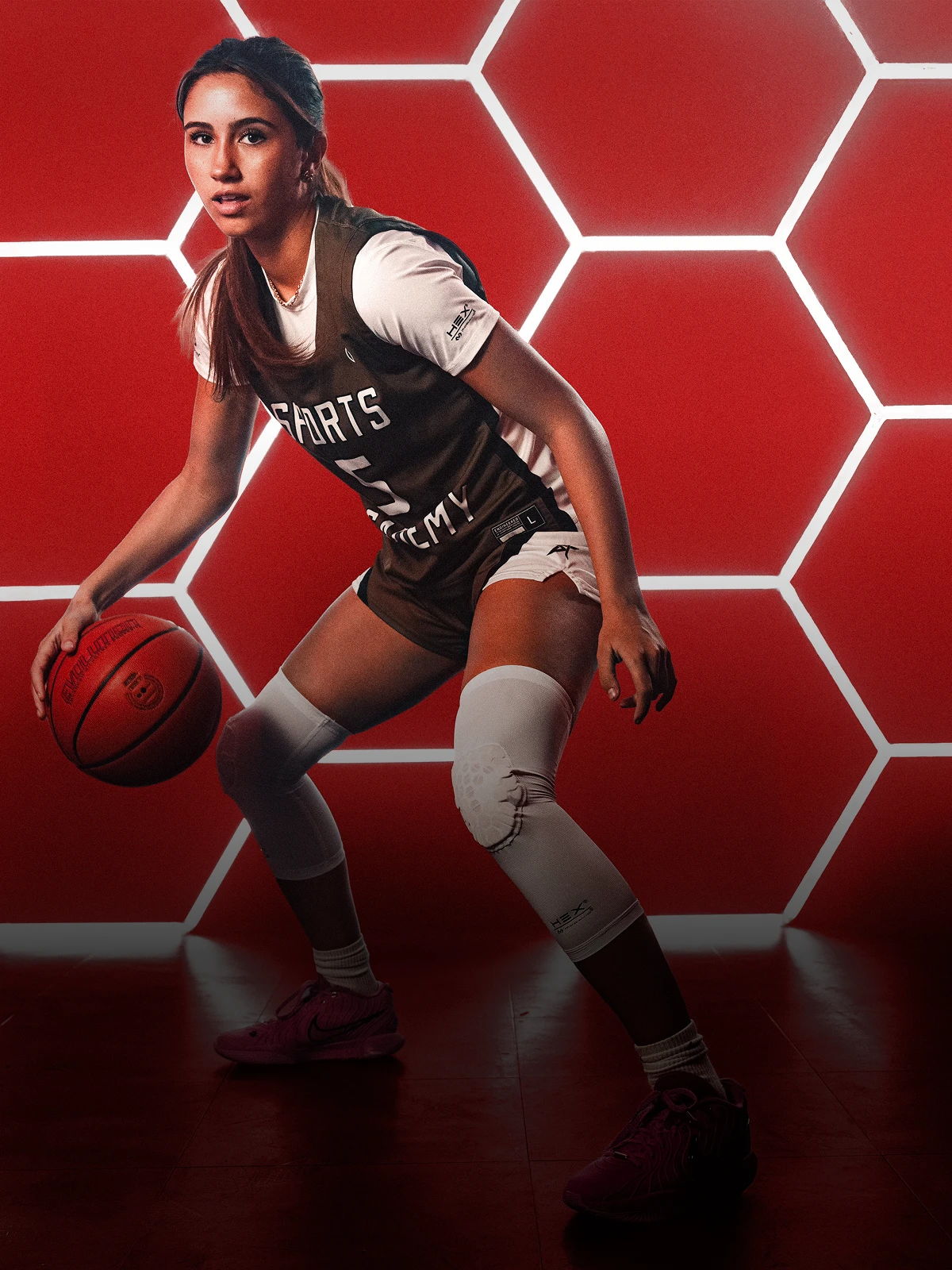 Basketball player in action, dribbling a ball against a geometric background.