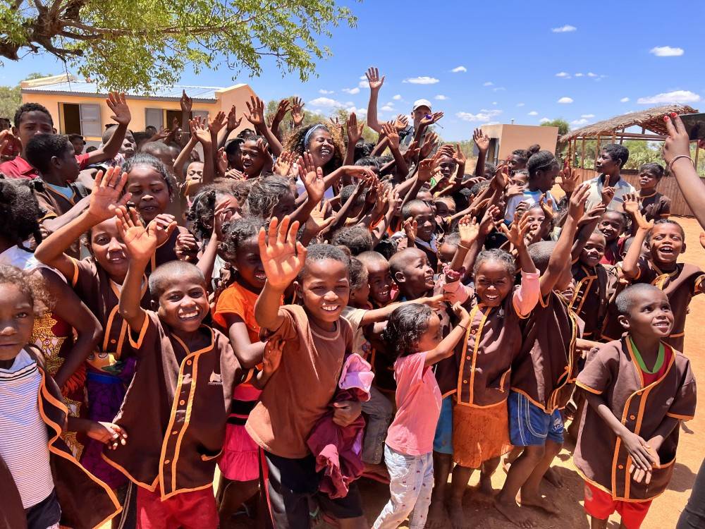 Afrikanische Kinder freuen sich und winken und die Kamera