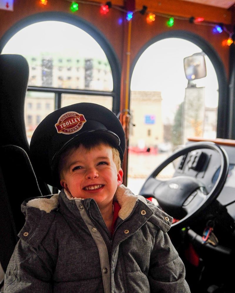 Child wearing a hat, smiling inside a decorated vehicle.