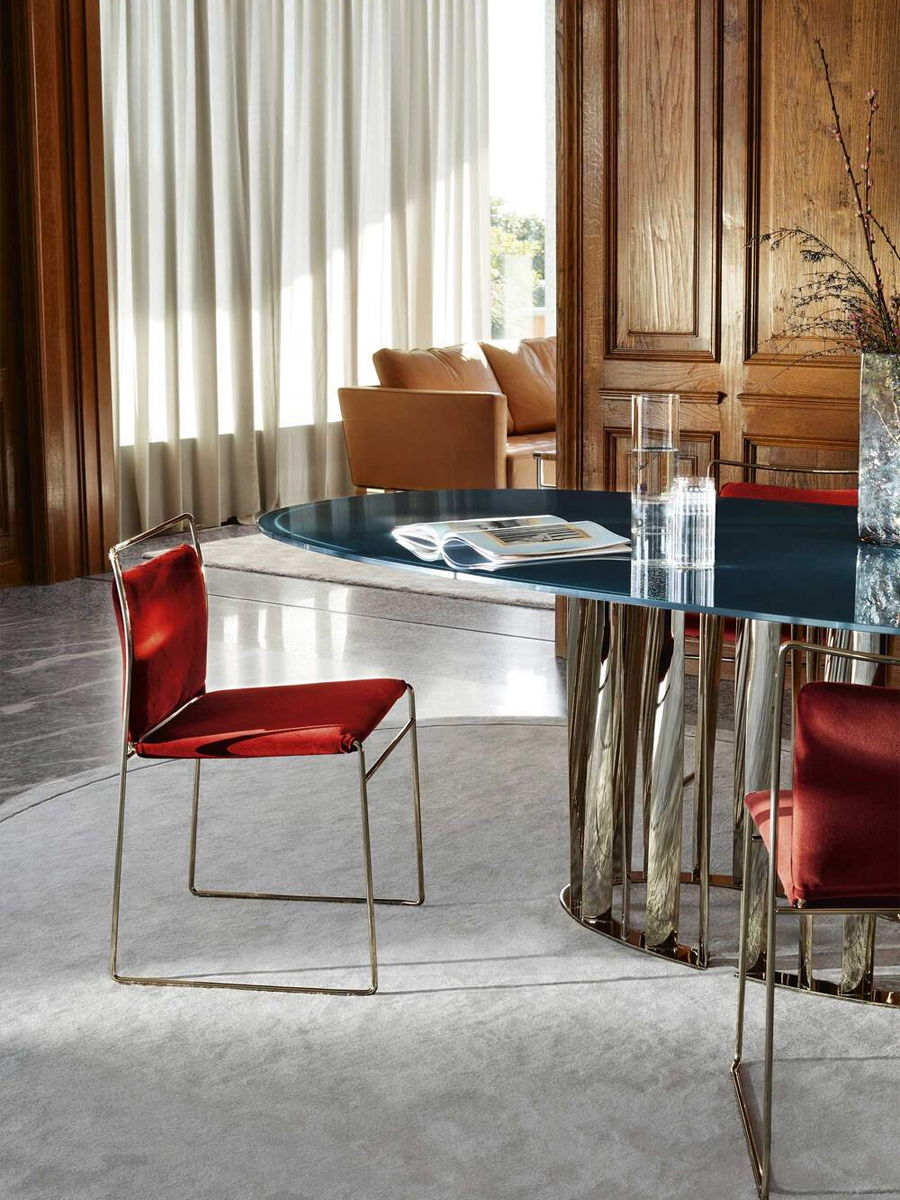 Modern dining area with a glass table and red chairs.