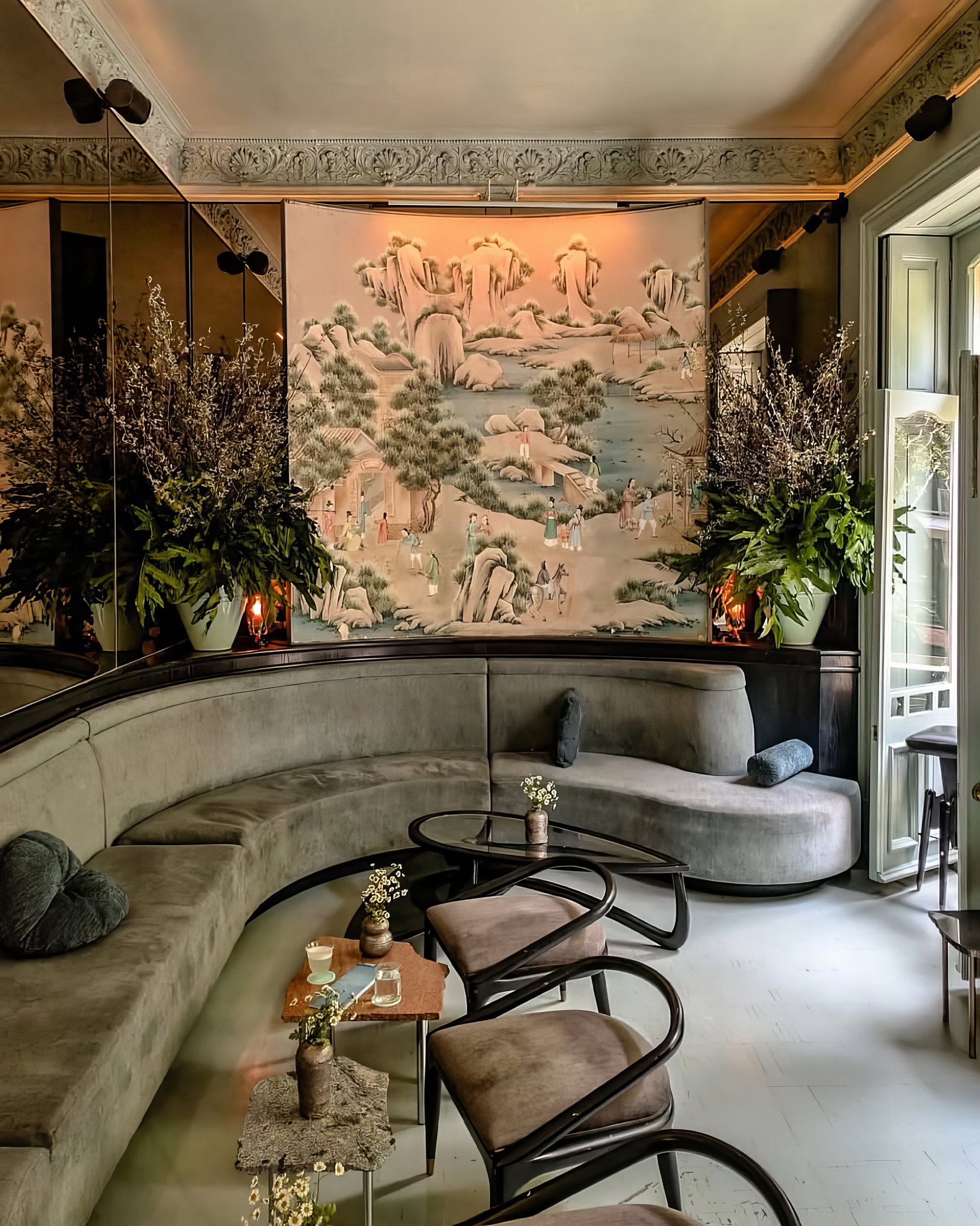 Elegant lounge with curved seating, decorative wall art, and lush plants.