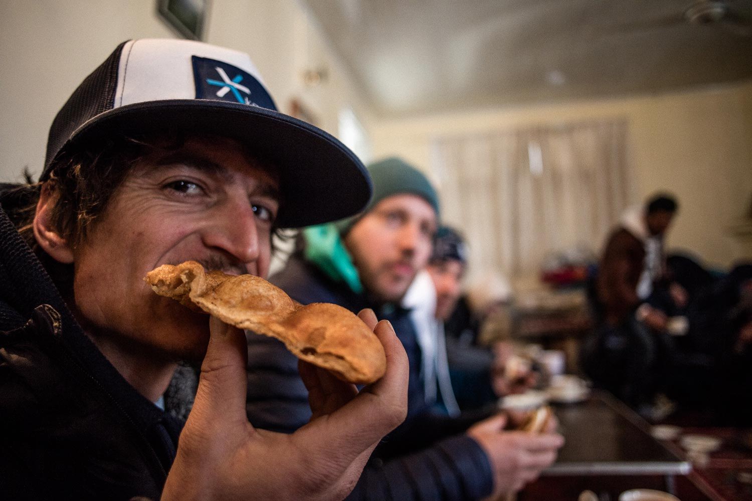 Person enjoying food in a cafe with others in the background.