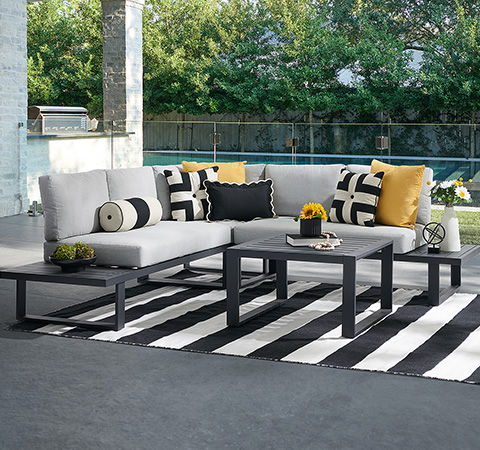 Modern outdoor seating area with cushions and a striped rug.