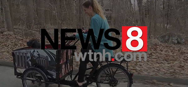 woman in bike with dog and news 8 logo