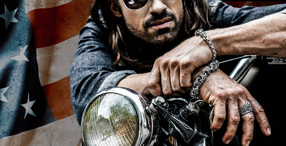 A man wearing NightRider Jewelry leaning on a motorcycle