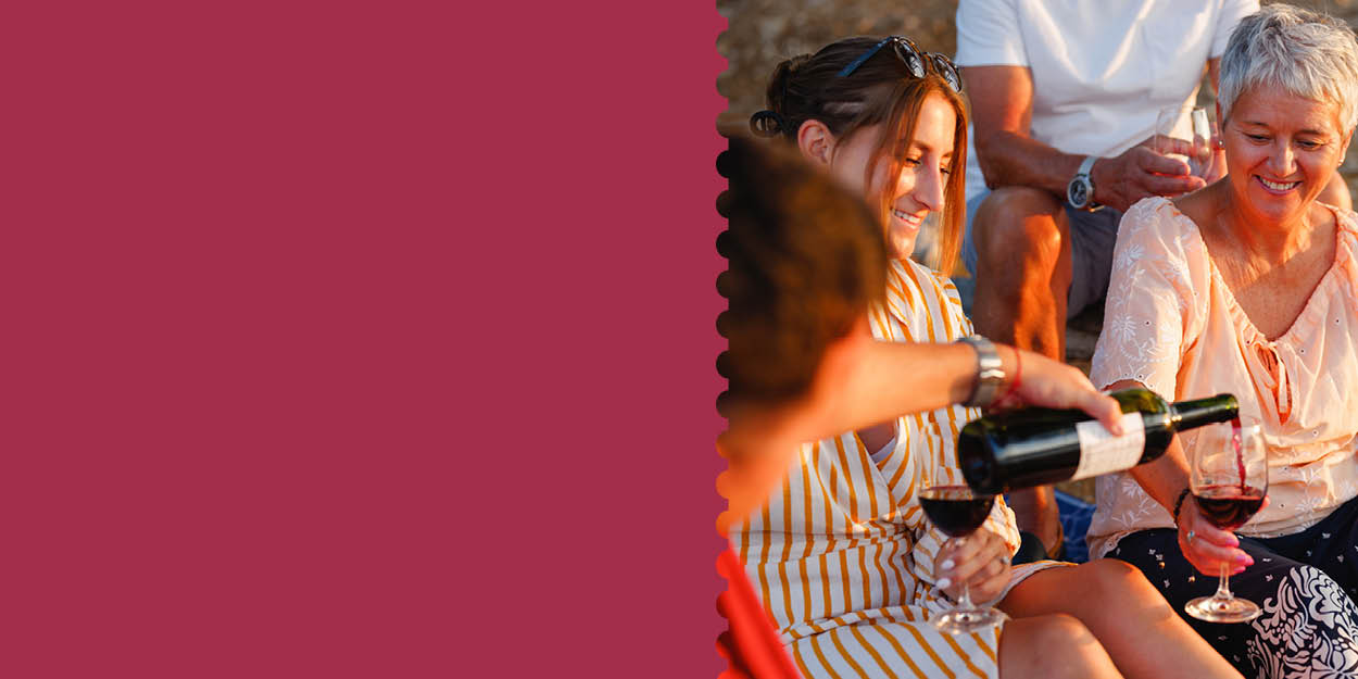 People enjoying wine together around a fire.