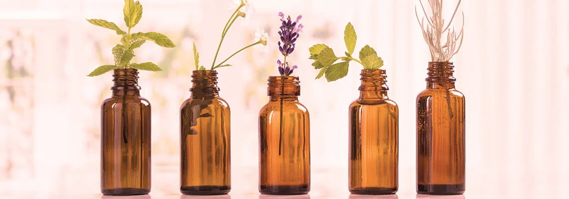 Five amber bottles with various plants inside.