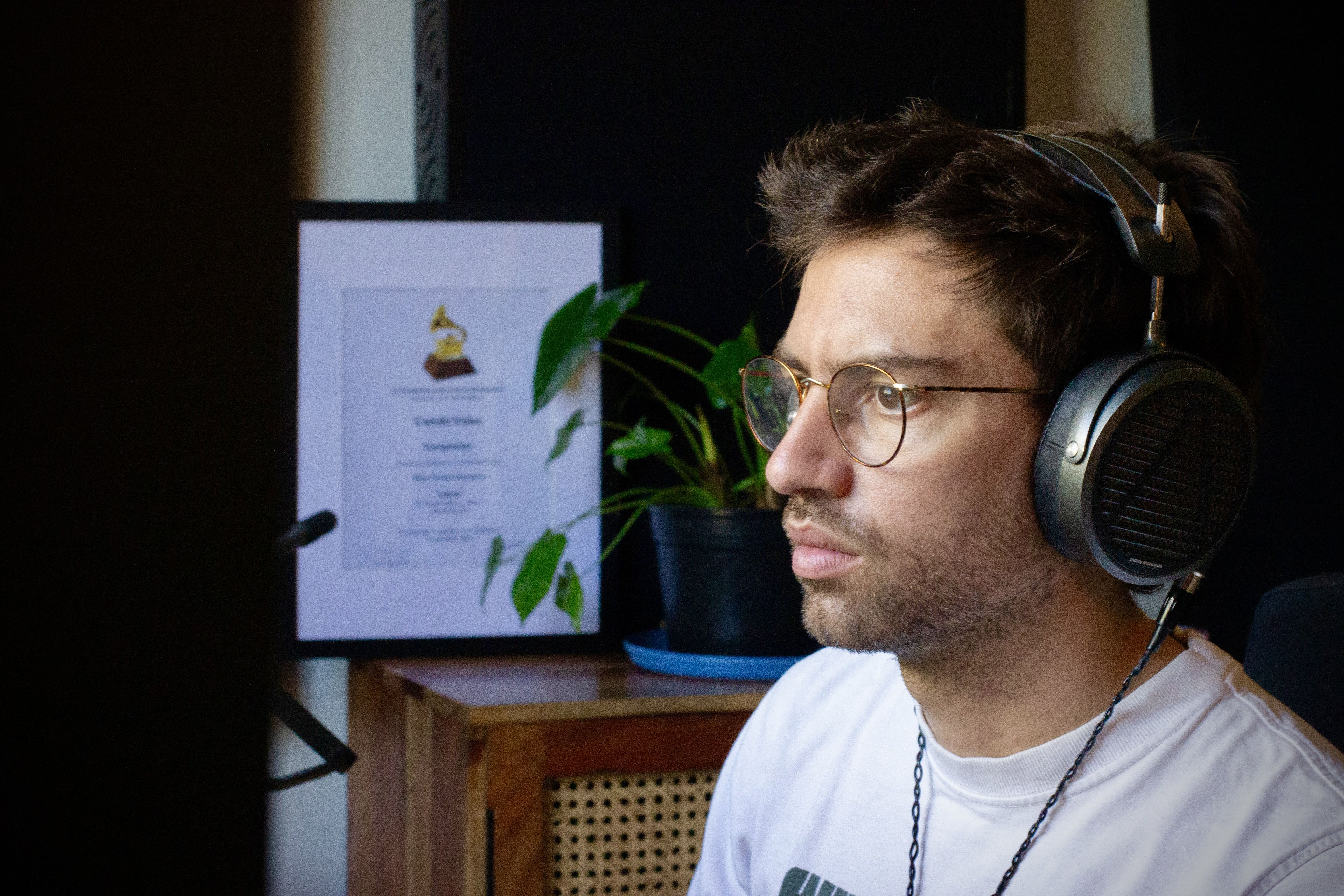 Camilio Velez with Audeze MM-500 headphones focused on a task, with a certificate in the background.