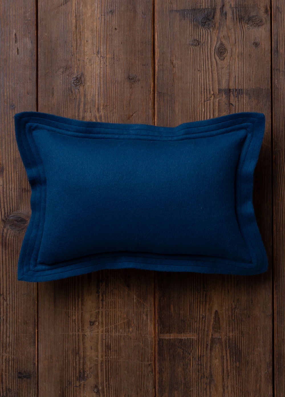 Navy blue pillow on wooden surface.