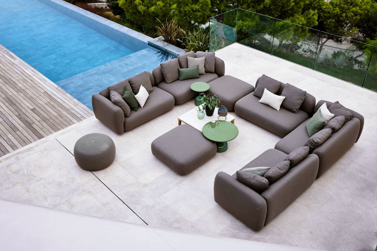 An expansive patio adjacent to a pool showcases a generously-sized sectional couch, providing a comfortable outdoor seating arrangement.