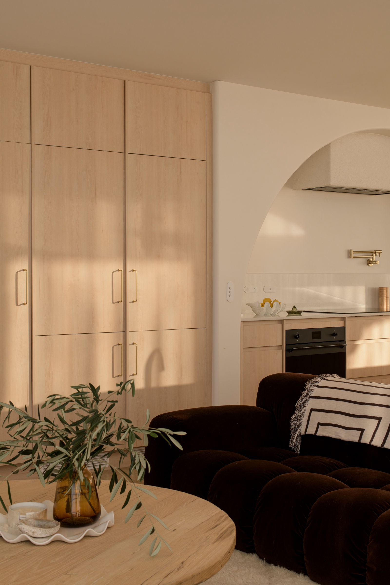 Cozy modern living room with cabinets, kitchen, and a round wooden table.