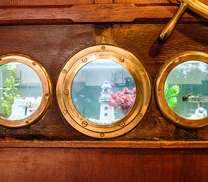 Portholes revealing an underwater scene with colorful plants and a lighthouse.