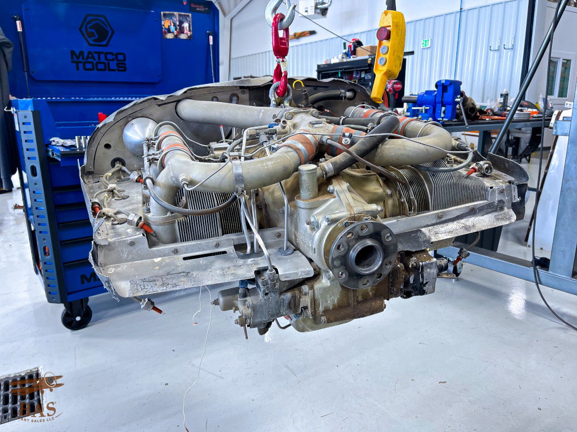 Engine on a lift in a workshop, surrounded by tools and equipment.