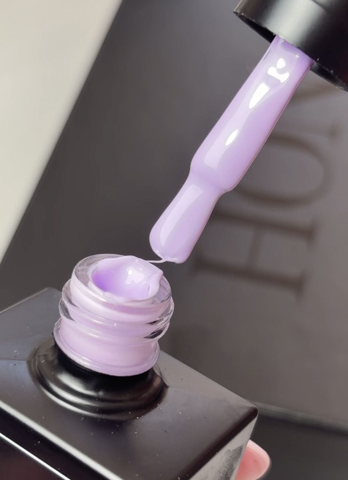 Purple nail polish being poured from a bottle.