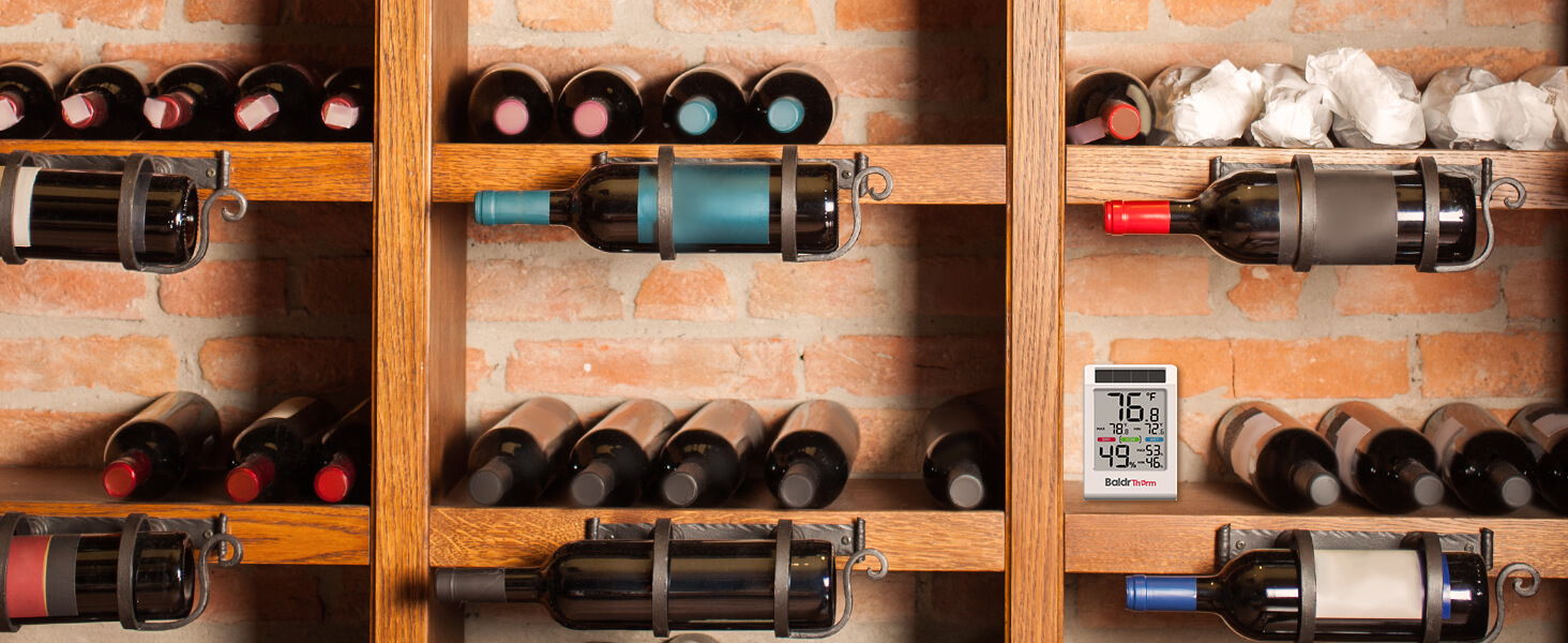 Wine bottles arranged on wooden shelves against a brick wall.