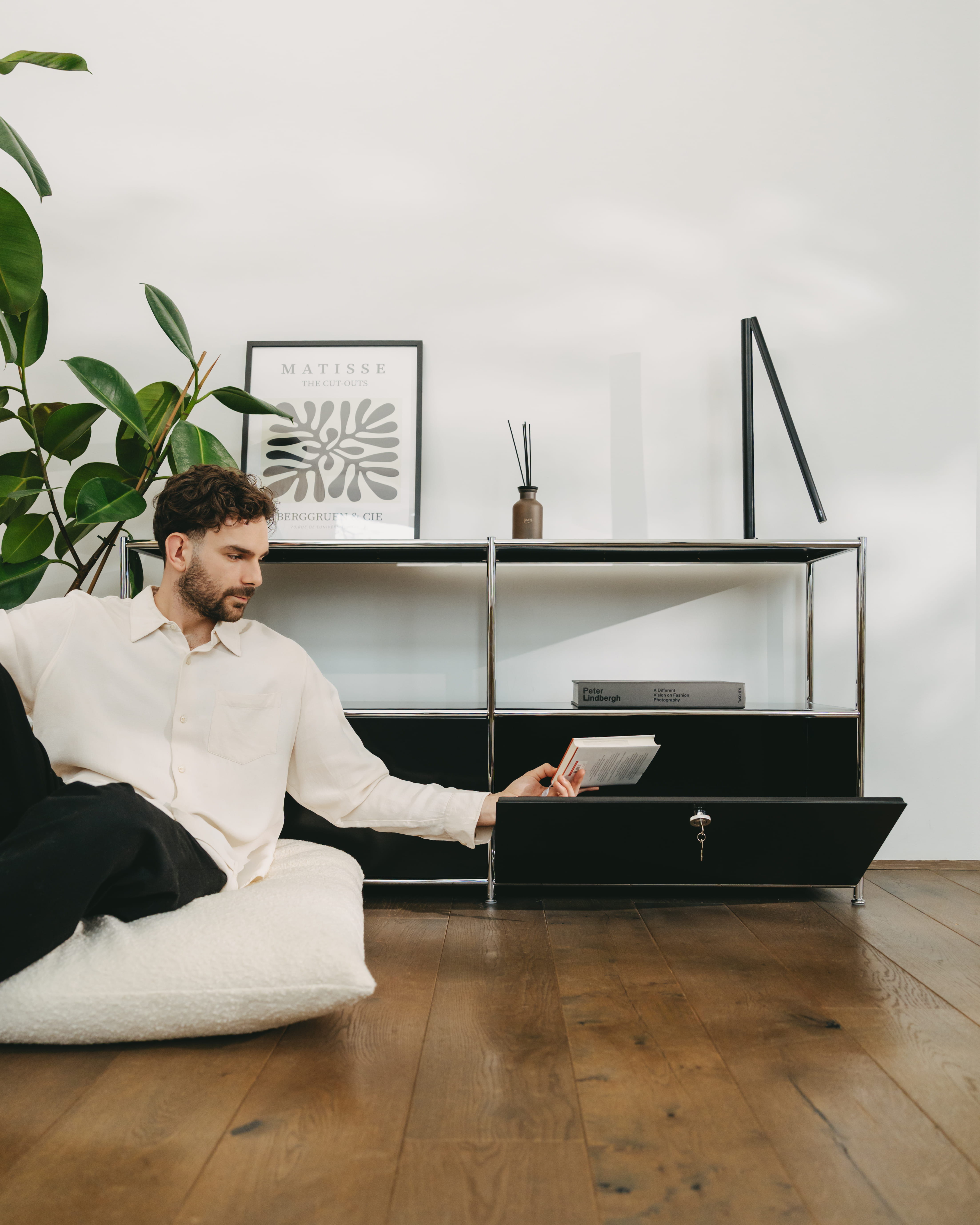 A man places his book on a "ofinto" Cubox dresser in his bright home office