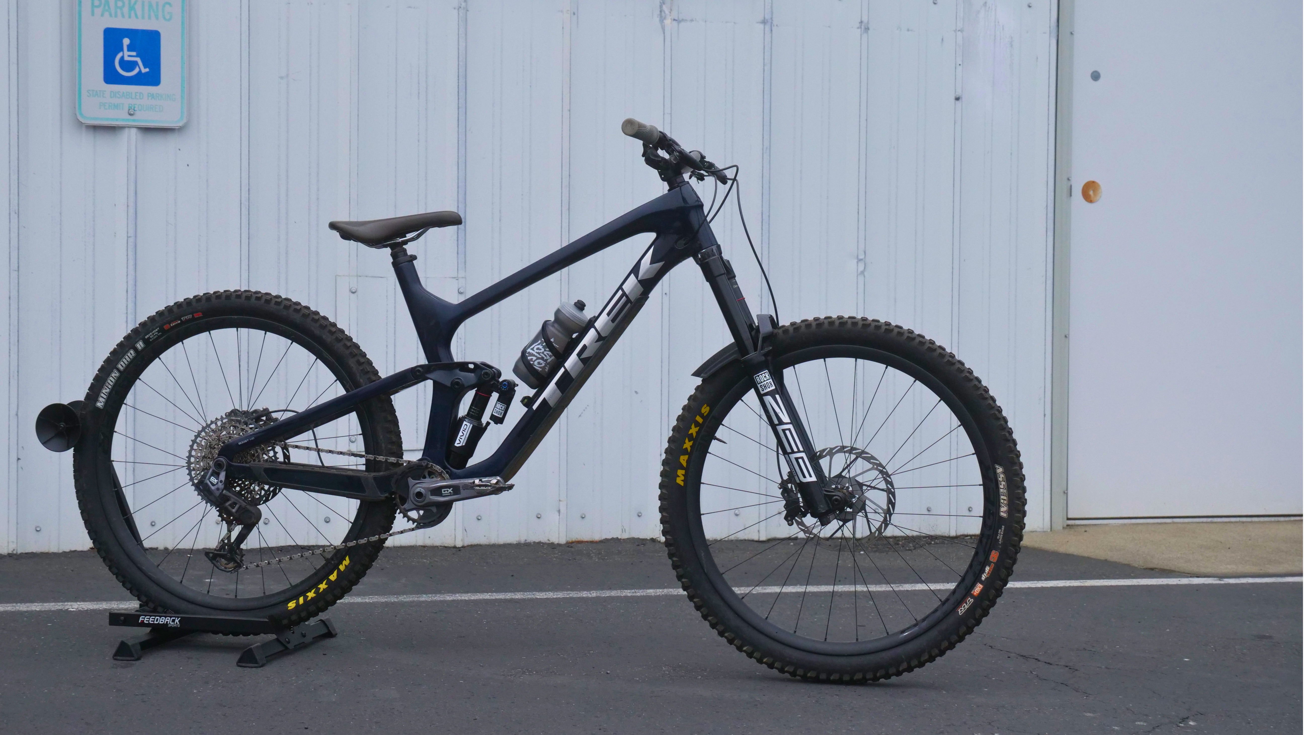 Mountain bike leaning against a wall with a parking sign in the background.