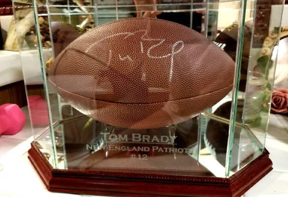 A signed Tom Brady football inside a glass display case.