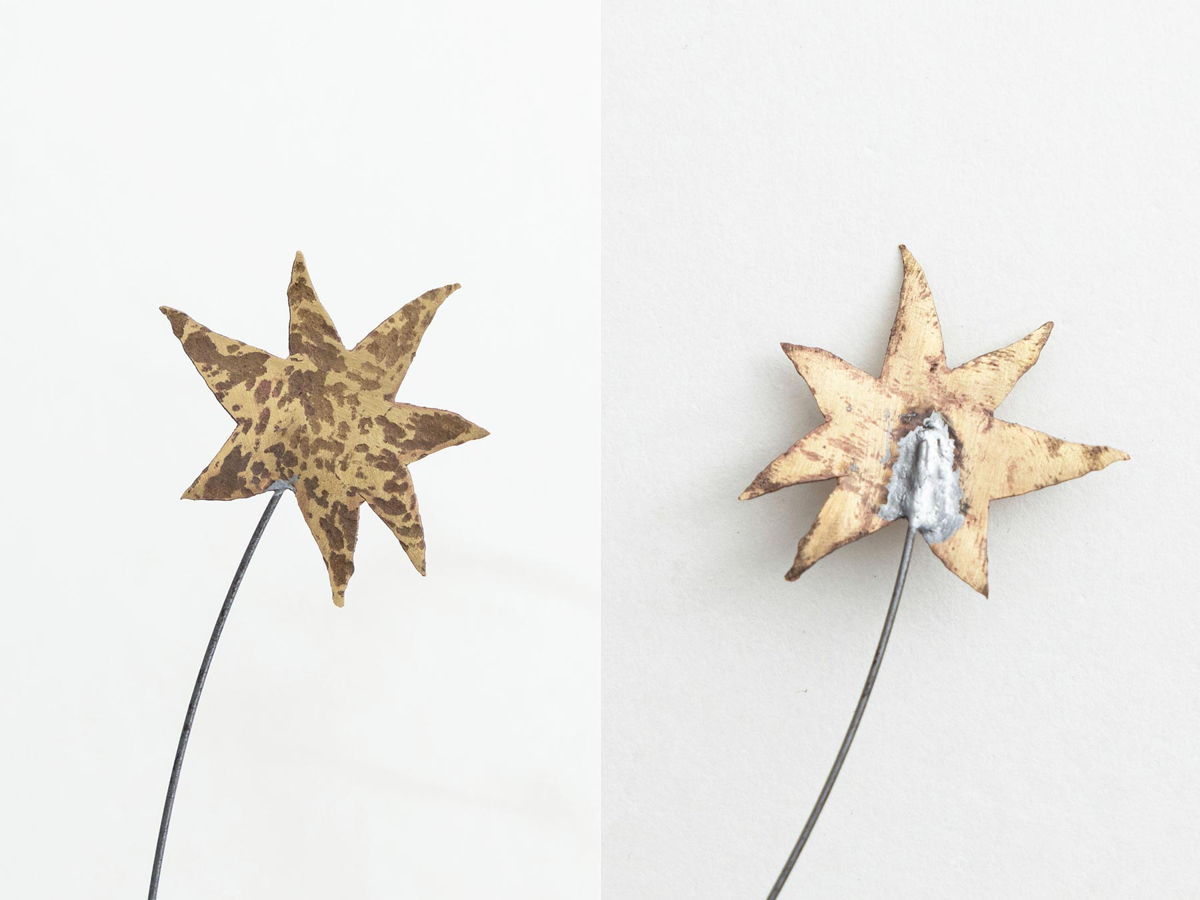 Two star-shaped flowers made from different materials on thin stems.