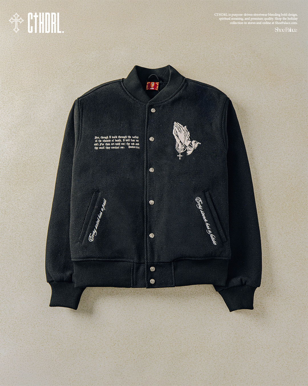 Black varsity jacket with graphic designs and text details.