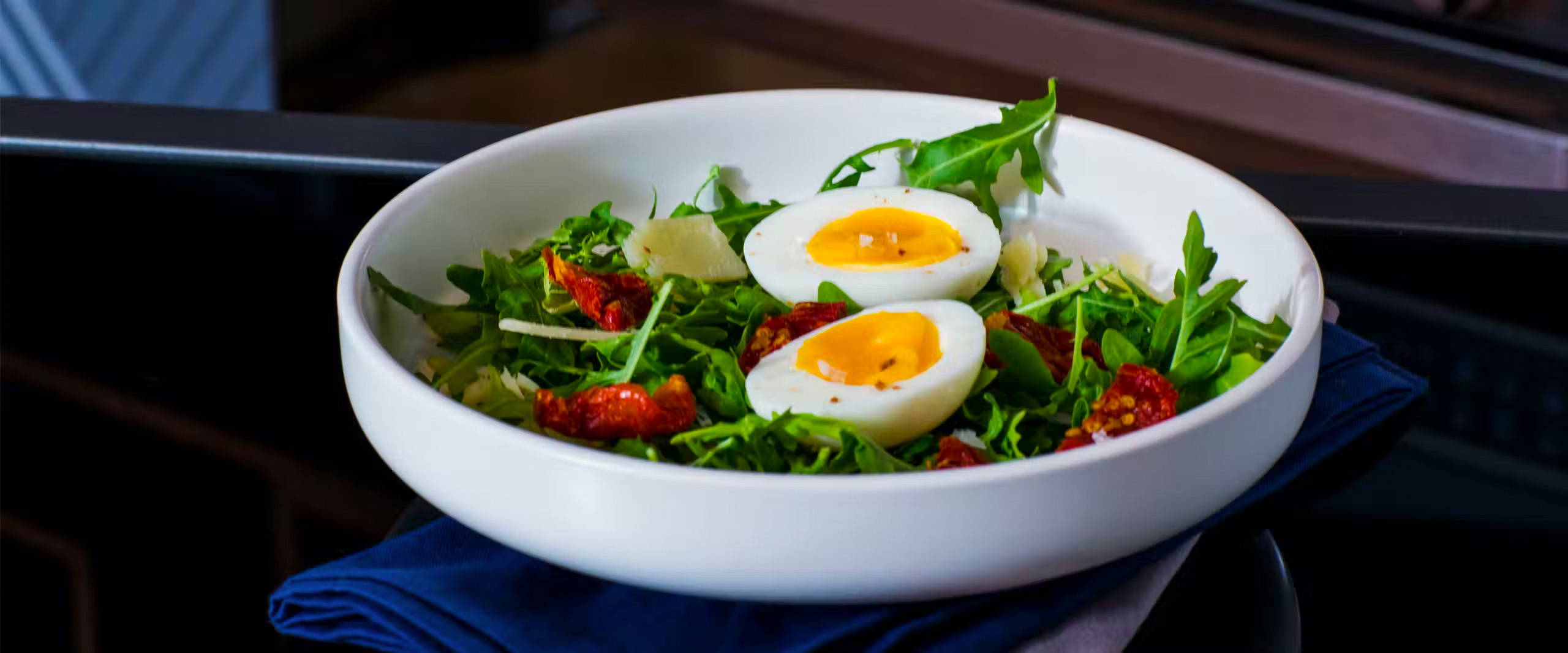 Bowl of salad with two boiled egg halves on top