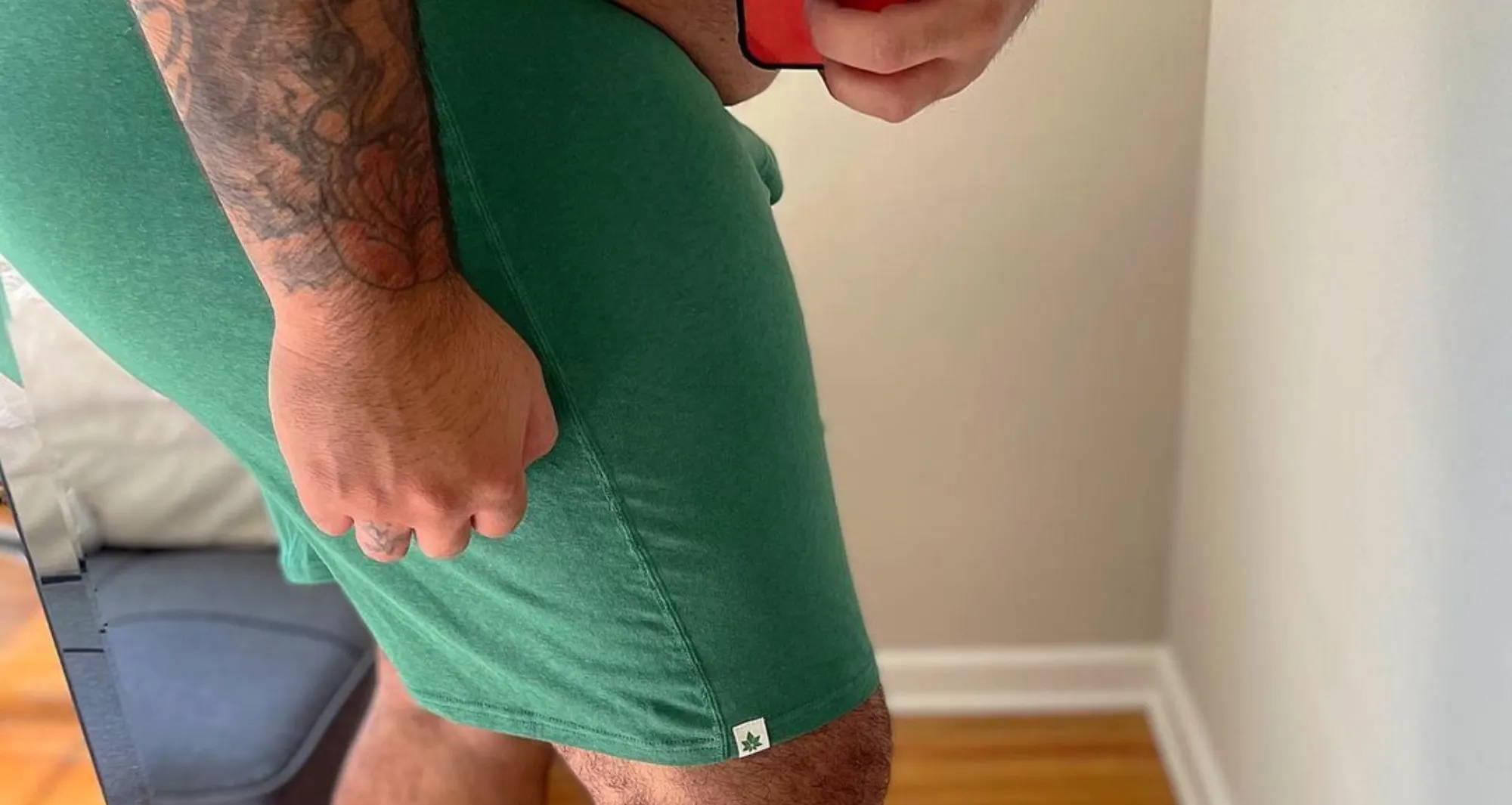  man with thicker thighs wearing green boxers with his tattooed arm in front taking a mirror selfie