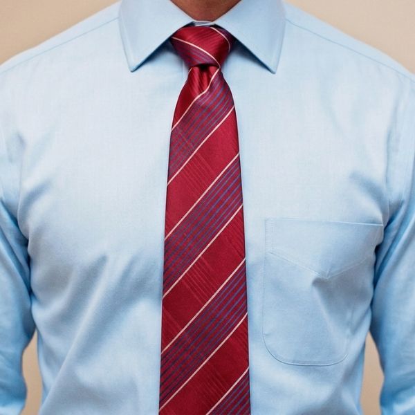 Man wearing a light blue dress shirt with a red plaid tie