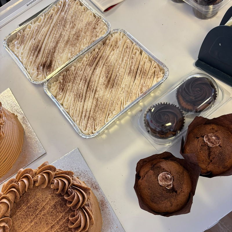 Ferraris Coffee and Just Love Food Company bakery samples featuring Tiramisu Traybakes, chocolate muffins, cupcakes and a decorated cake.