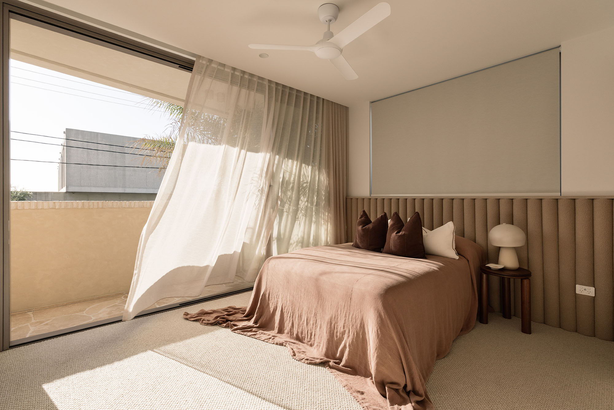 Modern bedroom with a brown bedspread and flowing curtains.