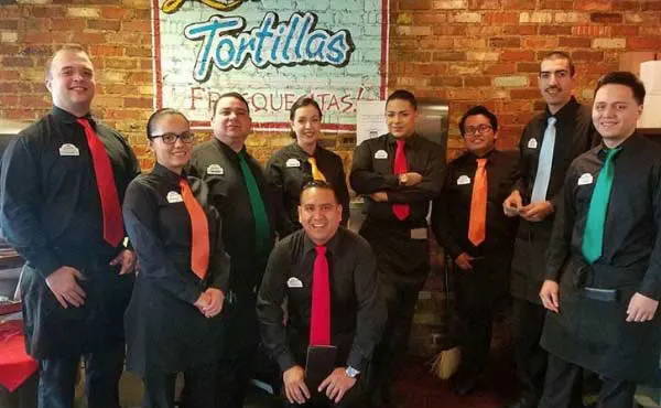 Waitstaff wearing all black with a colorful solid color tie