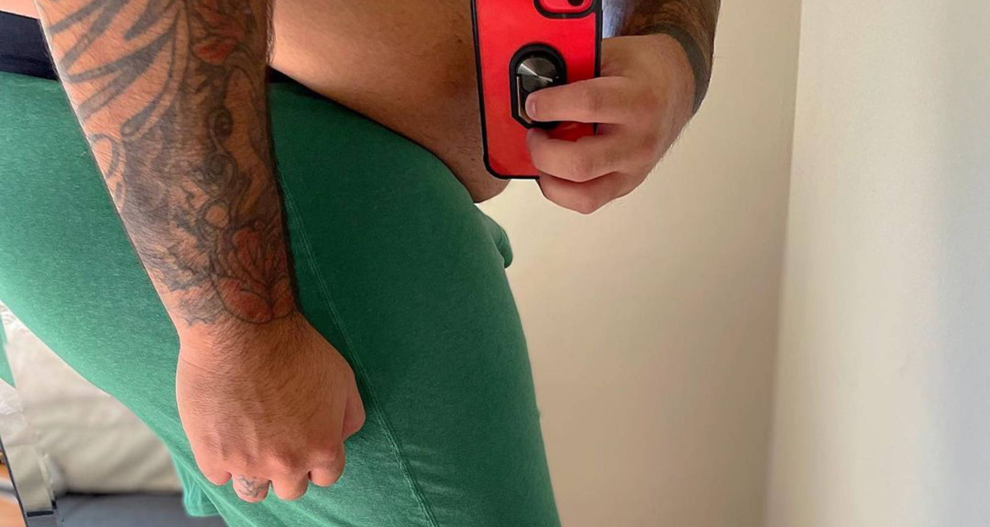  a plus size man wearing green boxers taking a mirror selfie from the side