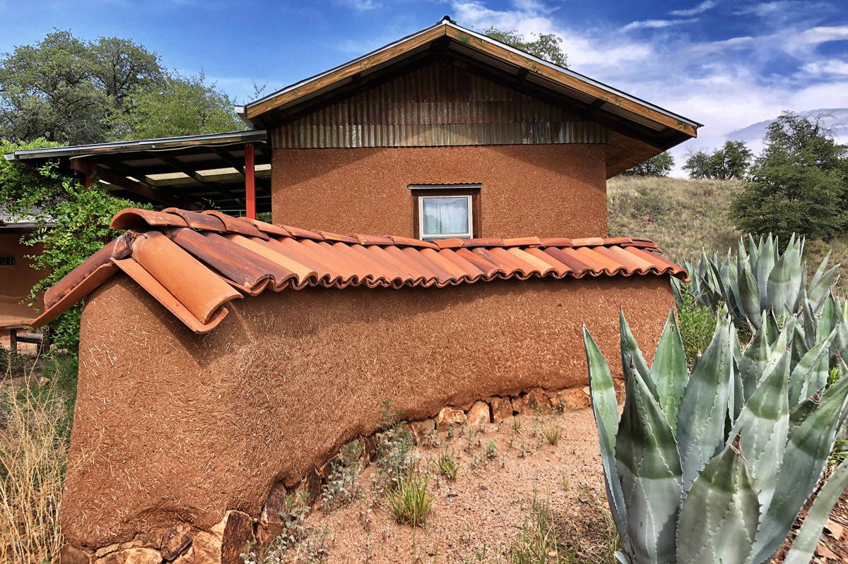 A straw clay border wall with a matching house in the background