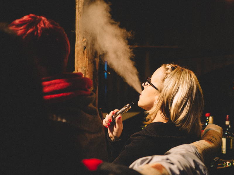 A young woman enjoys smoking a vape in public. 