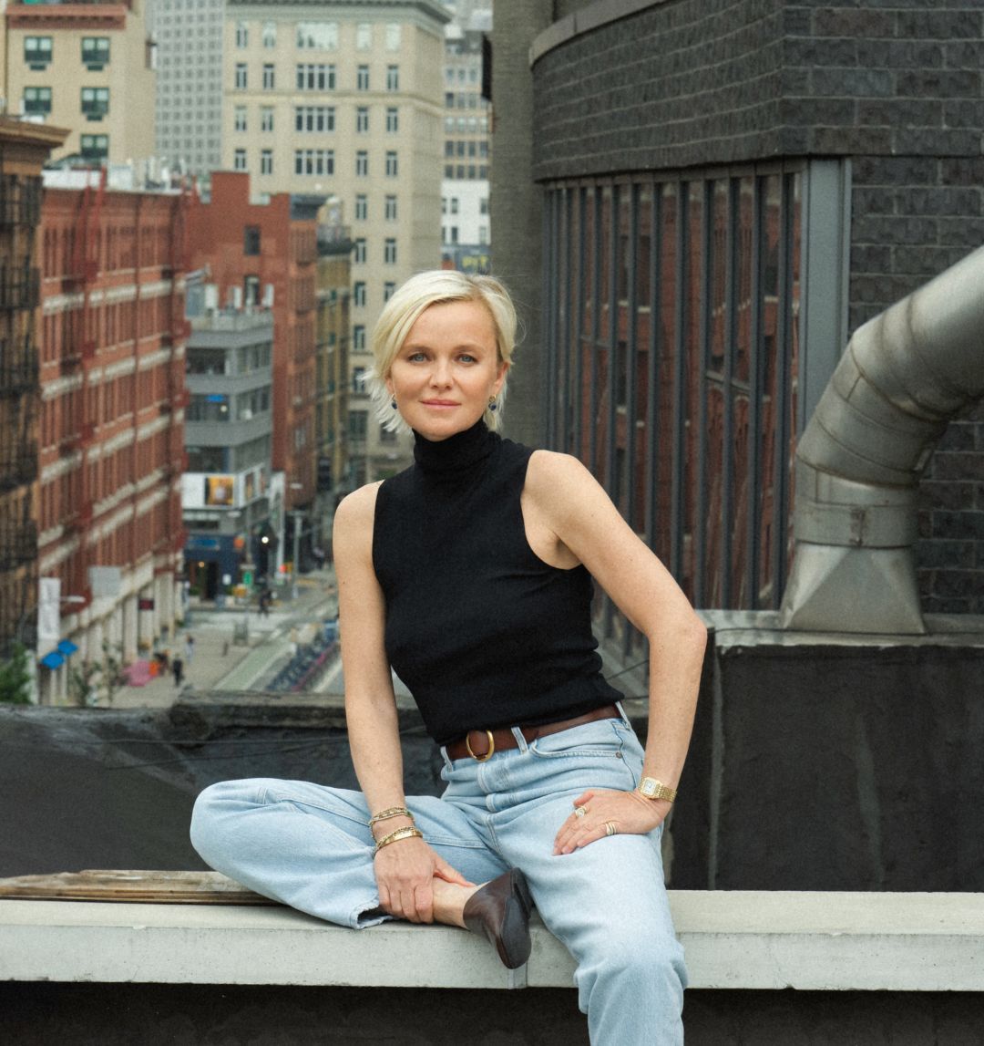 Person sitting on a rooftop with city buildings in the background.