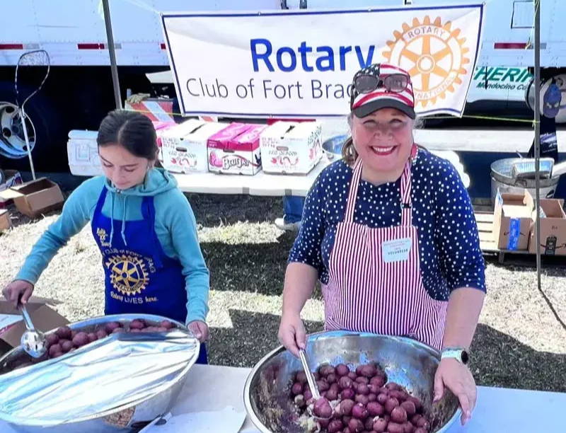 Young girl and Jennifer Bosma on right serving potatoes out of big bowls for the Salmon BBQ