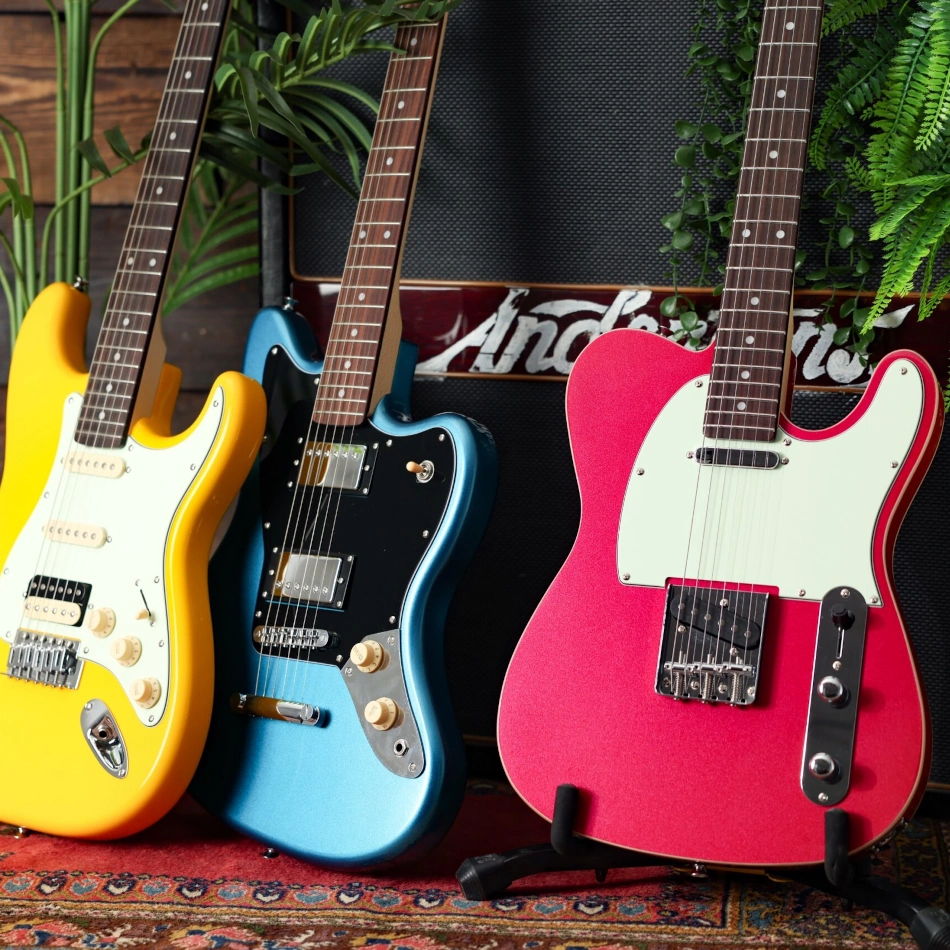 Three colourful EastCoast guitars lined up with plants in the background