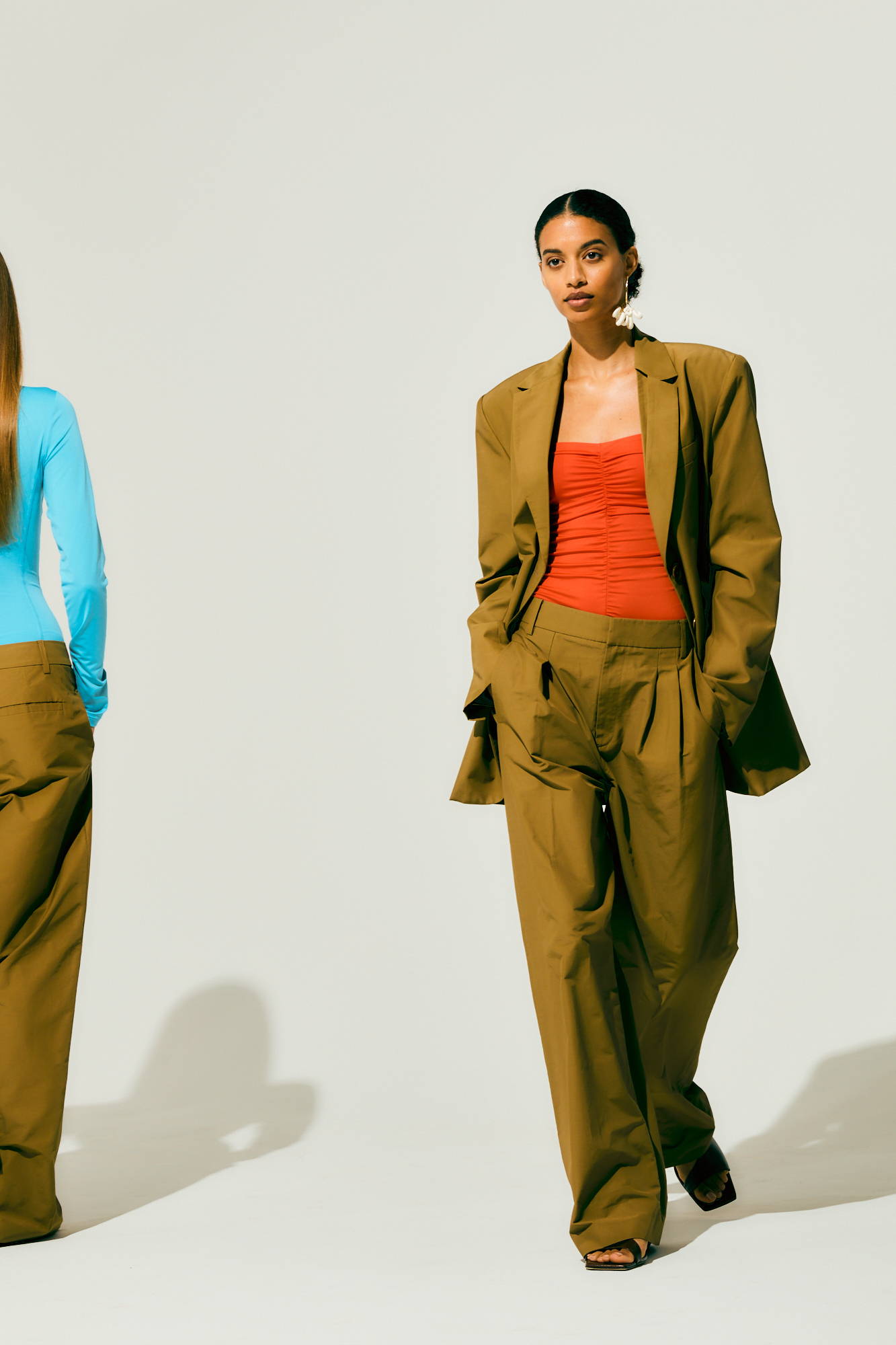 Two models wearing stylish outfits, posing against a neutral background.