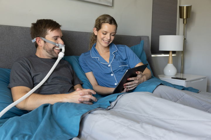 Couple in bed, man wearing CPAP mask