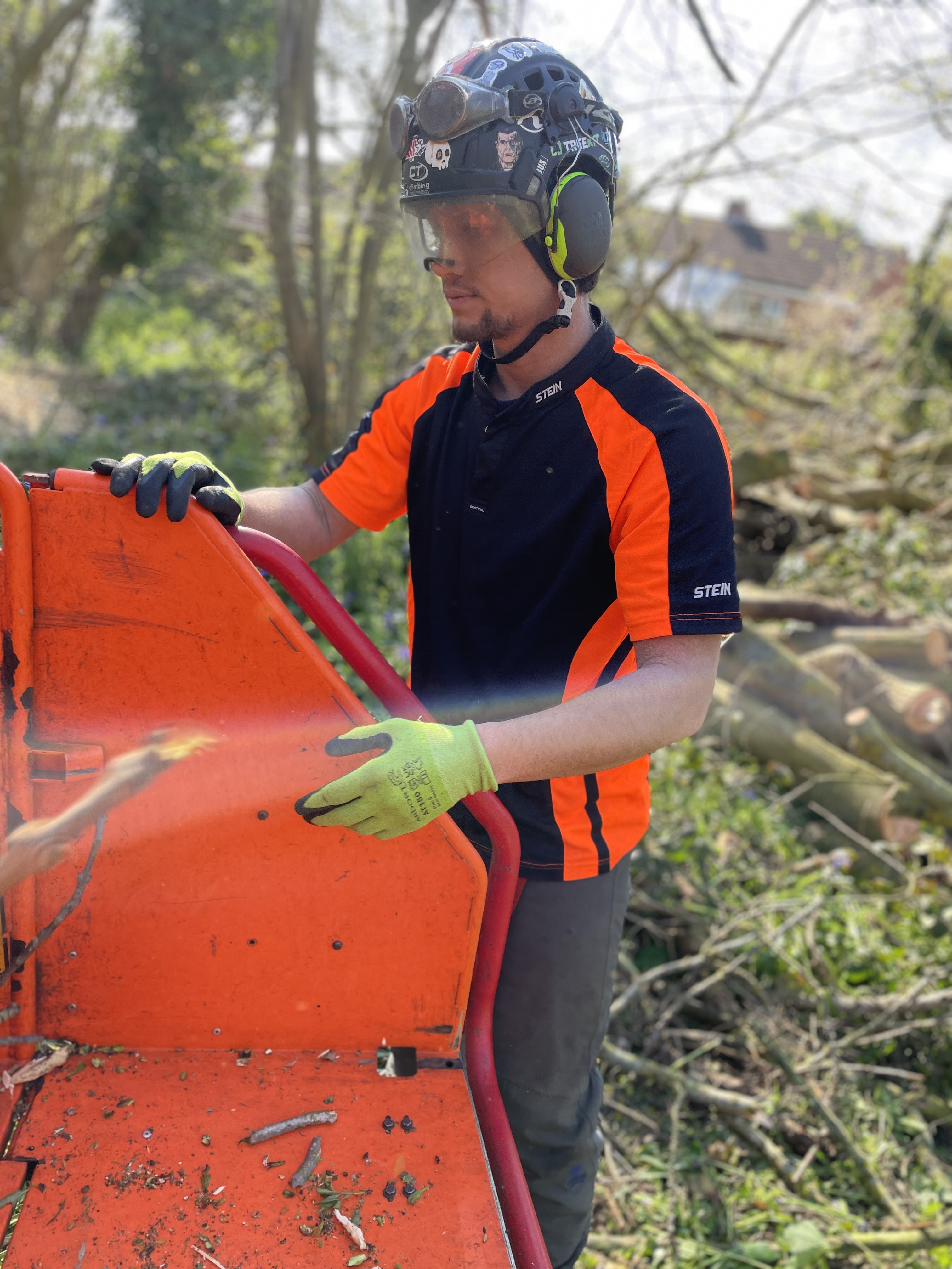 Person in safety gear operating machinery in a wooded area.
