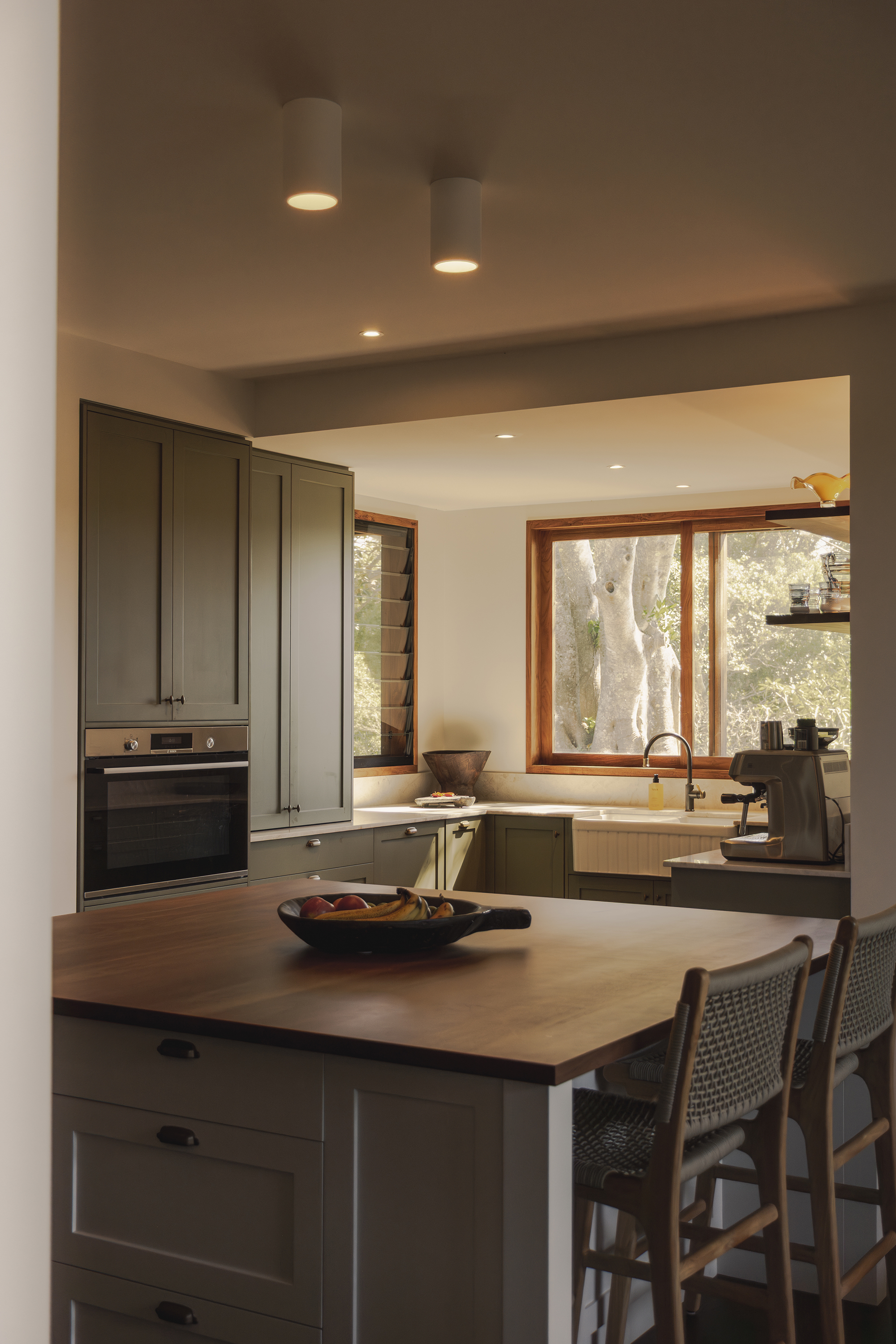 Modern kitchen interior with wooden accents and ceiling lights over an island bench